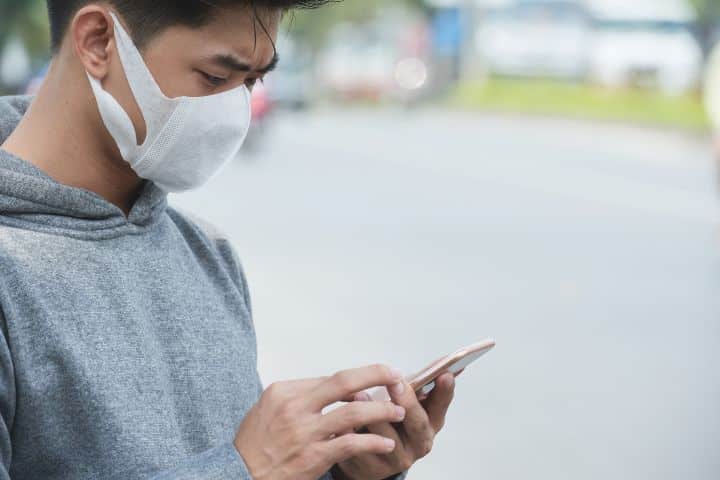 Cropped image of man in face mask checking messages in his smartphone Features straight to your phone is one way to protect CCTV cameras from theft