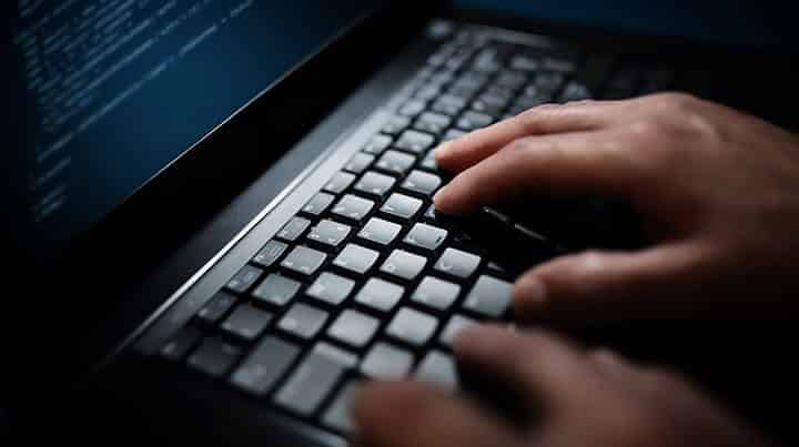 hacker typing on laptop to hack camera hacker typing on laptop to hack camera